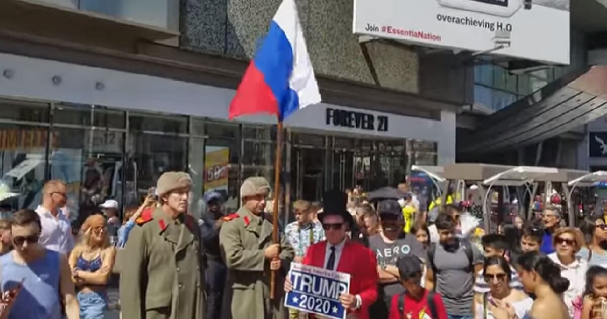 Men dressed as Russian guards are surrounded by a large crowd.