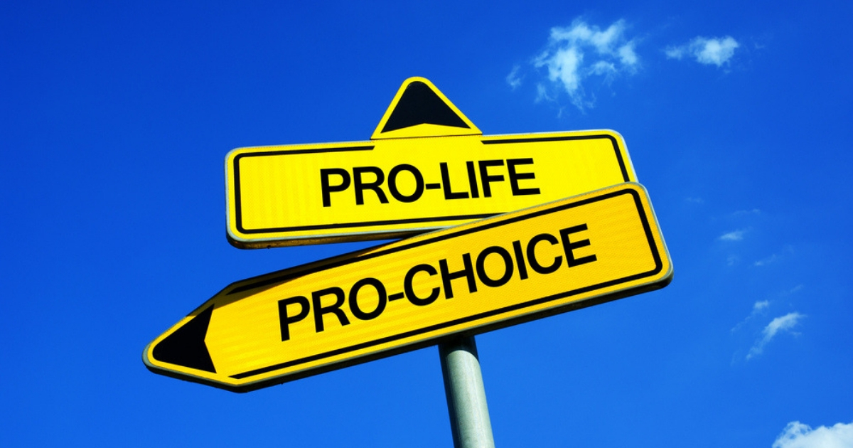 A fictional traffic sign with two options -- ethical dilemma of giving birth and forbidded termination or legal abortion. Freedom of mother vs value of human life