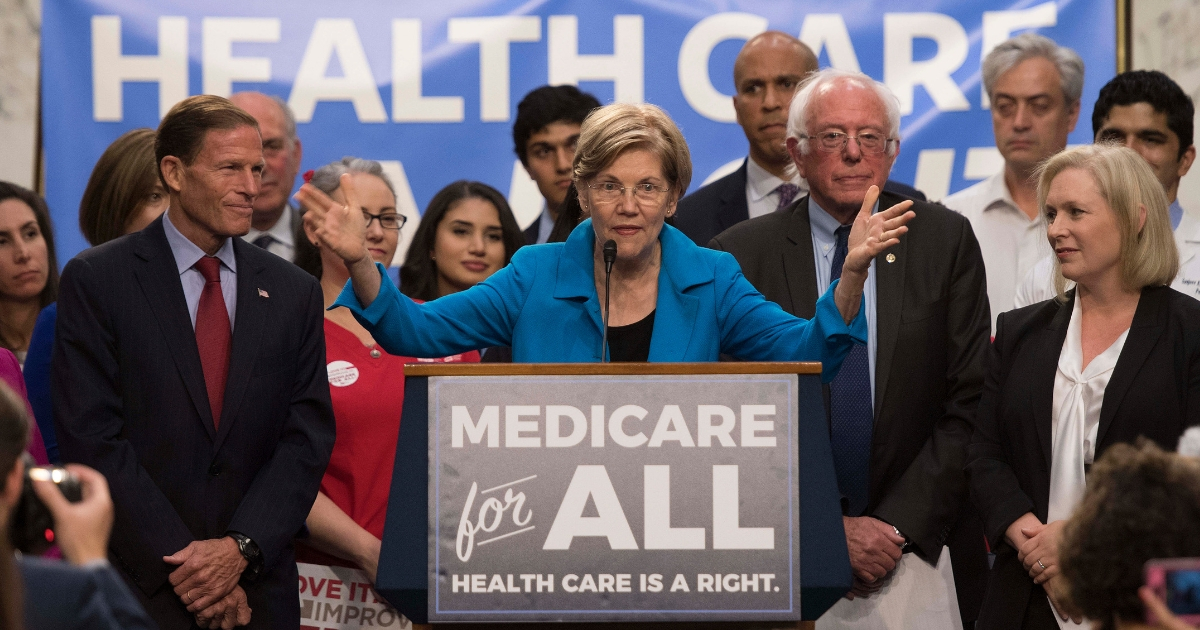 US Senator Elizabeth Warren (C), Democrat from Massachusetts, speaks with US Senator Bernie Sanders (2nd R), Independent from Vermont, as they discusses Medicare for All legislation on Capitol Hill in Washington, DC