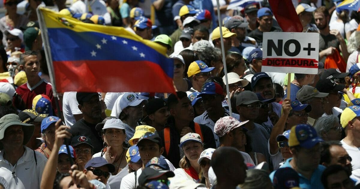 Anti-government protesters rally to demand the resignation of Venezuelan President Nicolas Maduro, as one holds a sign that reads in Spanish "No more dictatorship" in Caracas.