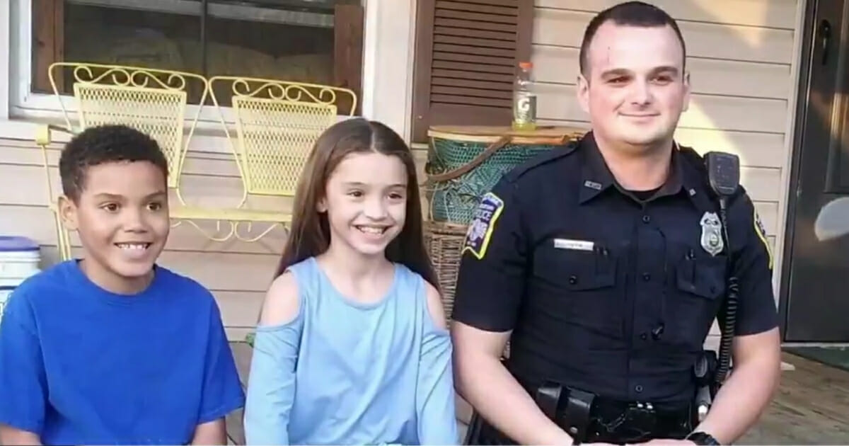 Two children sit on the porch with a police officer.