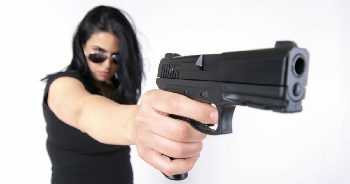 A woman takes aim with a handgun.