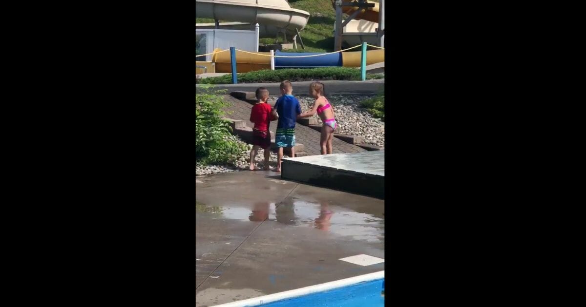 Friends help little boy with cerebral palsy walk at a water park.