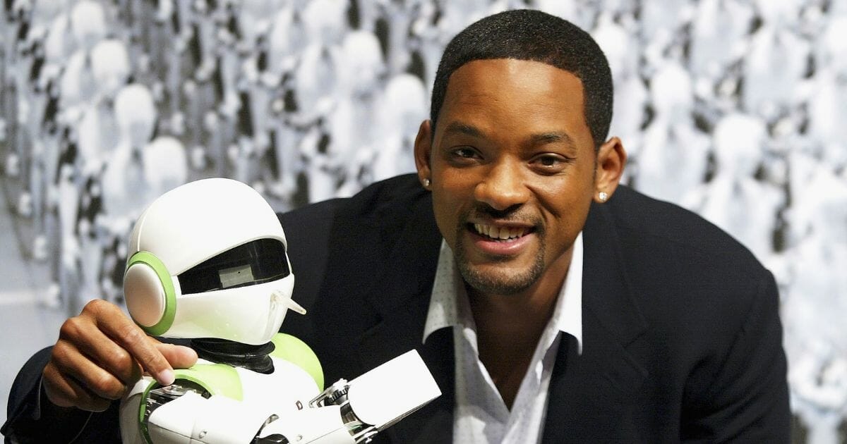 Actor Will Smith poses with humanoid robot PINO to promote the film "I, Robot" on Sept. 7, 2004, in Tokyo, Japan. A lab study in New Zealand suggests that "people perceive physically human-like robots to have a race and therefore apply racial stereotypes to white and black robots," according to CNN.