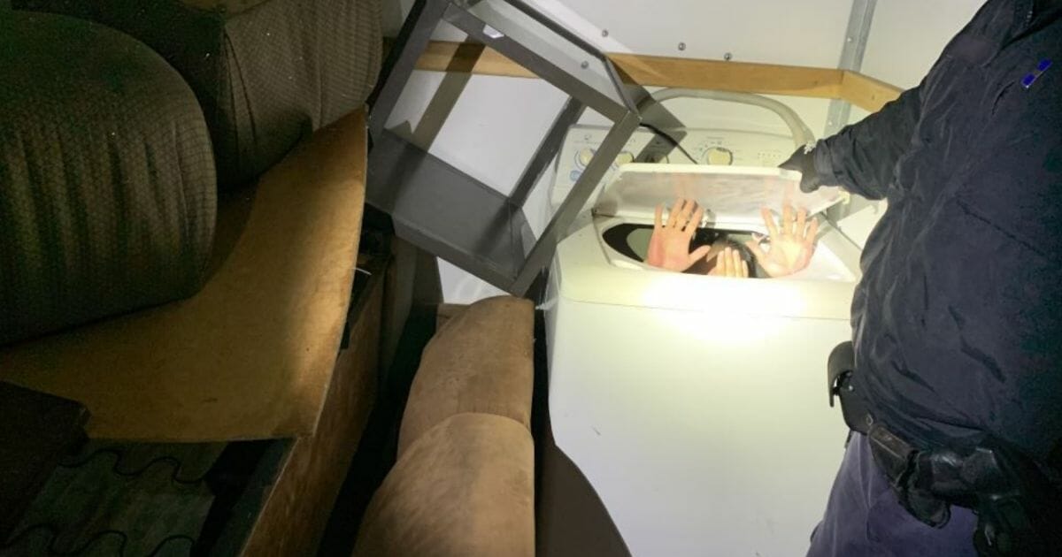 An immigrant is founding hiding in a washing machine inside a moving truck.