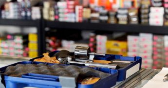 A stock photo of a revolver with rows of ammunition in the background is seen above.