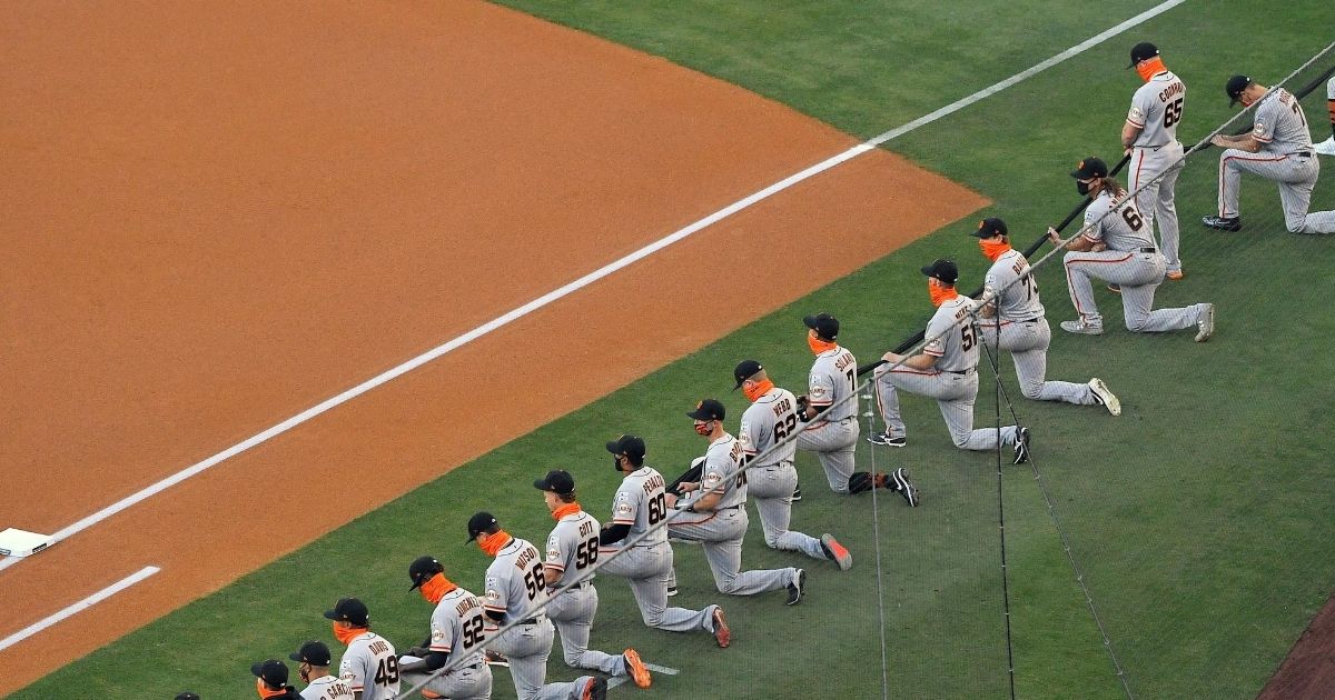 Sam Coonrod of the San Francisco Giants stands while his teammates kneel during a moment of silence prior to their Opening Day game against the Los Angeles Dodgers at Dodger Stadium on July 23, 2020.