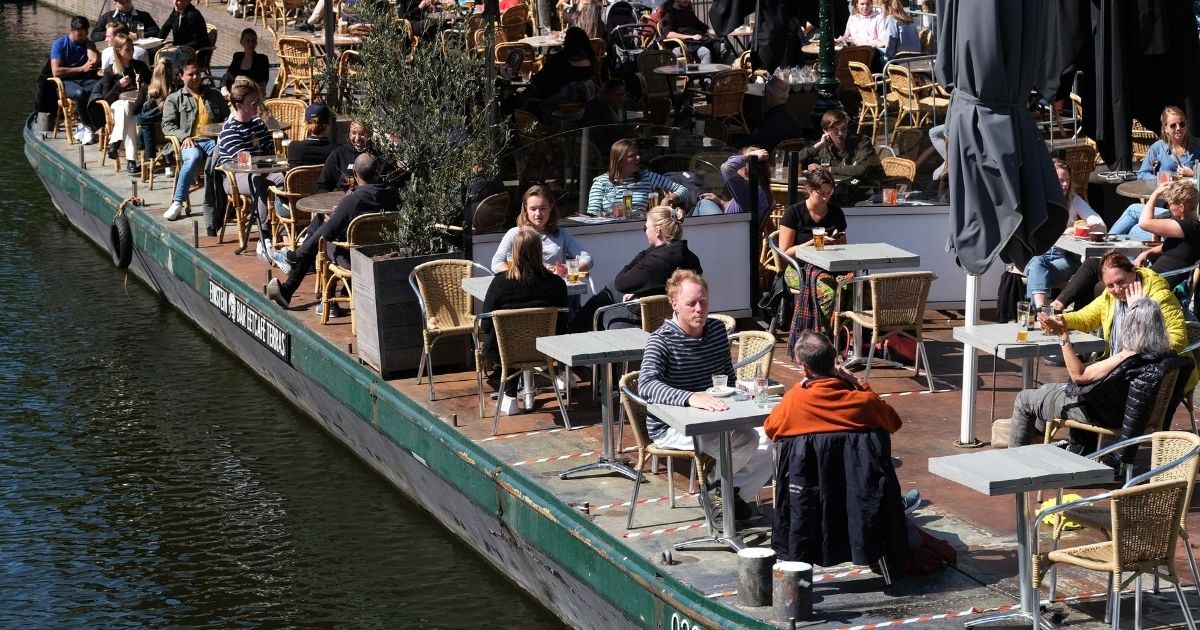 People eat and drink on an open terrace of a restaurant along a canal on June 9, 2020, in Leiden, Netherlands.