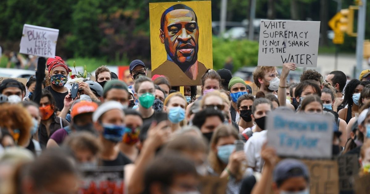 TOPSHOT - A protester holds up a portrait of George Floyd during a "Black Lives Matter" demonstration in front of the Brooklyn Library and Grand Army Plaza on June 5, 2020 in Brooklyn, New York, amid ongoing protests over Floyd's death in police custody. - The United States has seen more than a week of nationwide protests over the death in police custody of George Floyd, captured in a shocking video showing white officer Derek Chauvin kneeling on Floyd's neck for nearly nine minutes as he pleaded for his life.