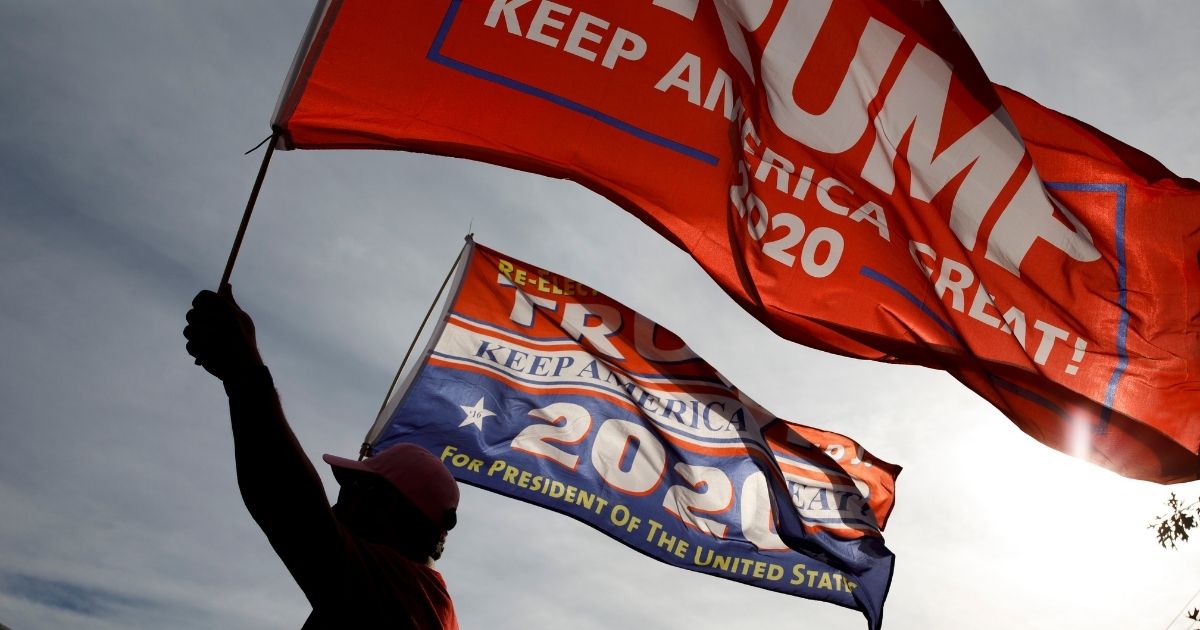 CHATTANOOGA, TN - NOVEMBER 4: A supporter of President Trump waves flags outside of McKenzie Arena, where U.S. President Donald Trump is holding a rally in support of Republican Senate candidate Rep. Marsha Blackburn, November 4, 2018 in Chattanooga, Tennessee. Blackburn, who represents Tennessee's 7th Congressional district in the U.S. House, is running in a tight race against Democratic candidate Phil Bredesen, a former governor of Tennessee. The two are competing to fill the Senate seat left open by Sen. Bob Corker (R-TN), who opted to not seek reelection.