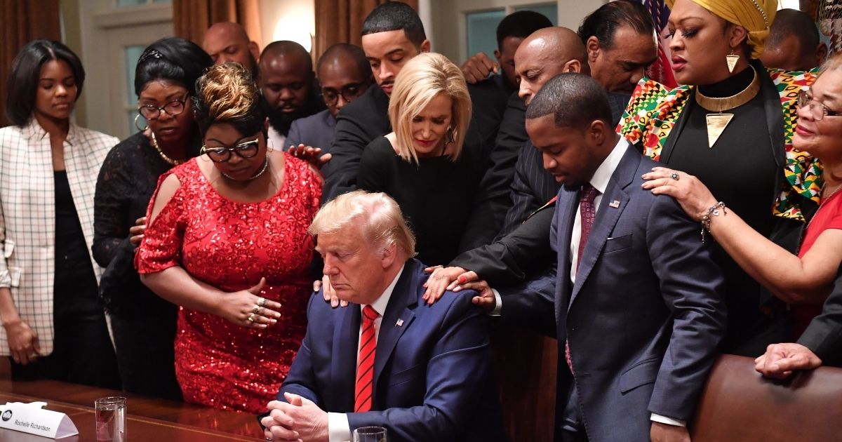 TOPSHOT - US President Donald Trump (C) stands in a prayer circle with African-American leaders in the Cabinet Room of the White House in Washington, DC, on February 27, 2020.