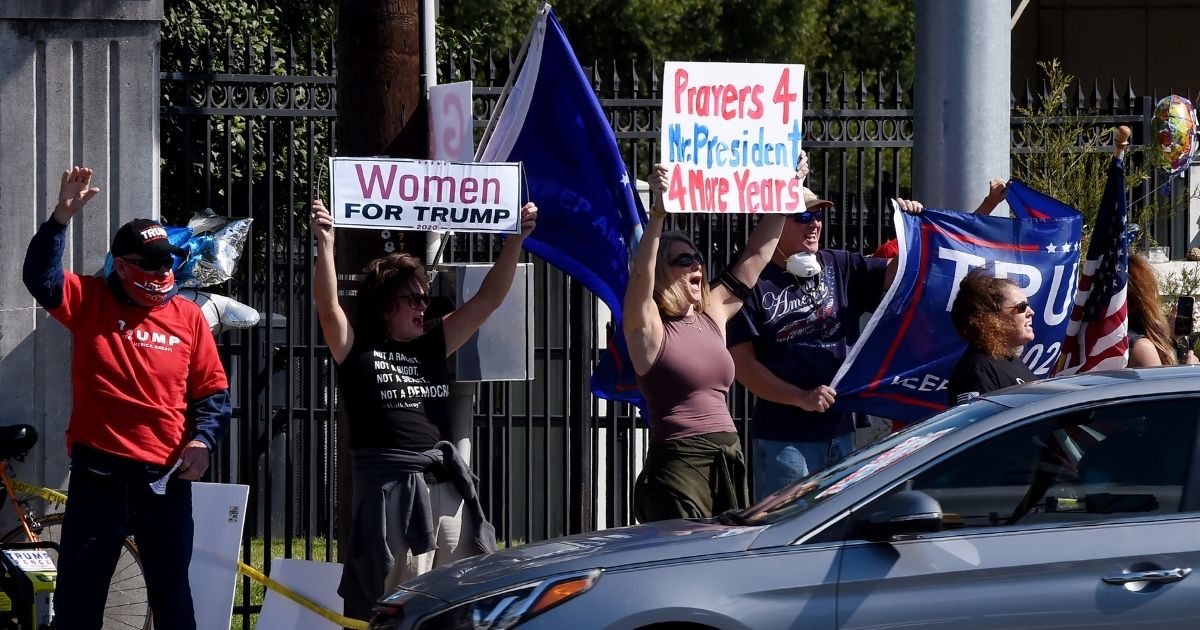 Supporters of US President Donald Trump wave placards outside Walter Reed National Military Medical Center on October 5, 2020 in Bethesda, Maryland. - Donald Trump's doctors were to decide whether he is recovered enough to leave hospital and continue Covid-19 treatment at the White House, as the president signalled his determination to return to the election campaign with an early morning tweetstorm.