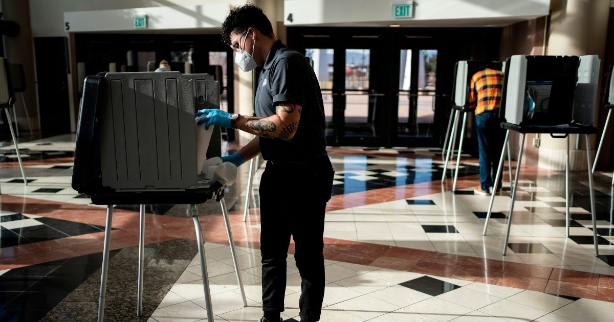 A poll worker sanitizes a voting booth in Denver on Election Day on Nov. 3, 2020. Colorado is one of 15 states that have signed onto the National Popular Vote Interstate Compact.