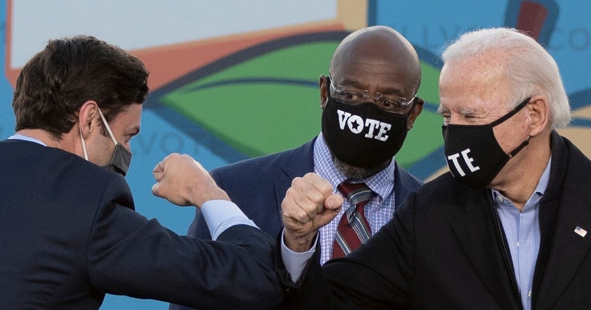 Democratic Senate candidates Jon Ossoff, left, and the Rev. Raphael Warnock, center, and presumptive President-elect Joe Biden bump elbows on stage during a rally outside Center Parc Stadium in Atlanta on Monday.