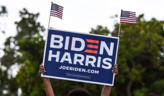 A supporter of Joe Biden holds a sign as they wait for former President Barack Obama to speak at a Biden-Harris drive-in rally in Miami on Oct. 24, 2020.