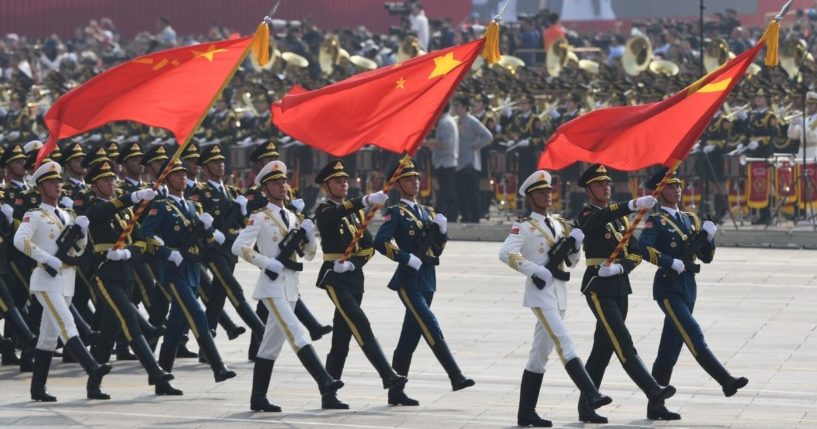 Chinese soldiers march with the national flag, flanked by the flags of the Communist Party of China and the People's Liberation Army during a military parade at Tiananmen Square in Beijing on Oct. 1, 2019.