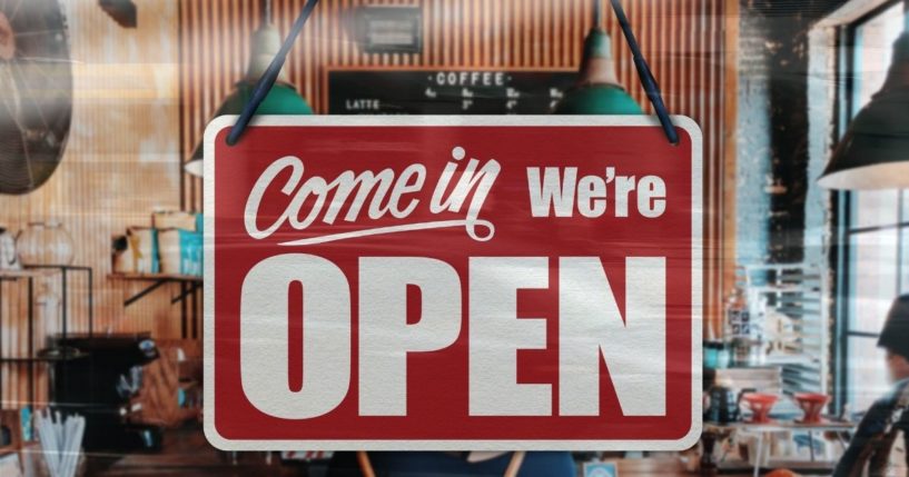 A business sign that says 'Come in, we're open' is seen on a restaurant window.