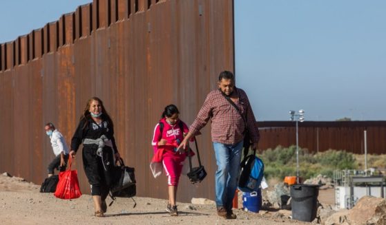 A family of asylum seekers from Colombia walk through an opening in the wall at the US Mexico border to turn themselves in to U.S. Border Patrol agents on May 13 in Yuma, Arizona.