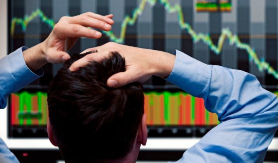 In this stock photo, an investor looks at stock prices dropping on a screen.