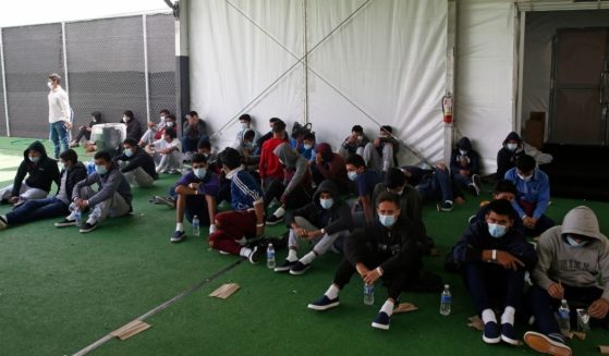 Young minors sit on the ground of a holding facility in Donna, Texas, on March 30.