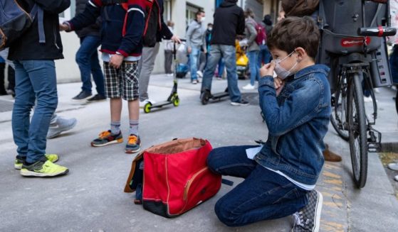 A boy adjusts his face mask before entering primary school in Paris April 26.