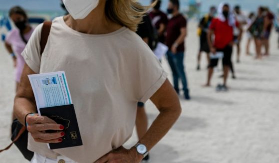 A woman holds her passport as she waits in line to get the Johnson & Johnson COVID-19 vaccine at a pop-up vaccination center at the beach, in South Beach, Florida, on May 9, 2021.