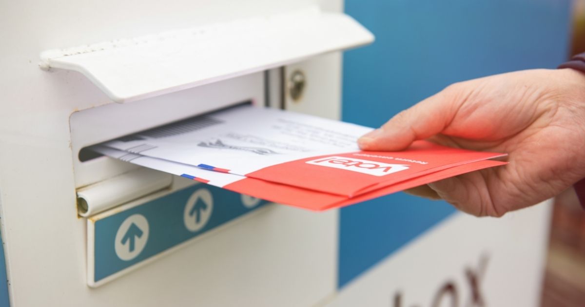 A man places ballots in a drop box in the above stock image.