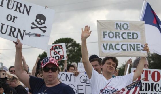 In this Monday file photo, demonstrators at Houston Methodist Baytown Hospital in Baytown, Texas, wave at cars that honk at them to support their protest against a policy that says hospital employees must get vaccinated against COVID-19 or lose their jobs.