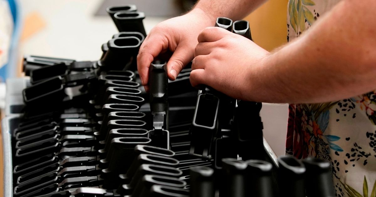 A worker places pistol grips for an AR-15 style rifle on a cart at Davidson Defense in Orem, Utah, on Feb. 4, 2021.