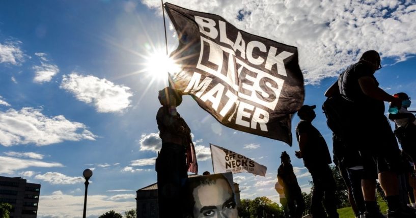 A woman holds a Black Lives Matter flag during an event in remembrance of George Floyd outside the Minnesota State Capitol on May 24, 2021, in Saint Paul, Minnesota.