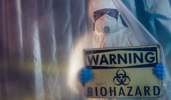 This stock photo portrays a man holding up a biohazard warning sign. One official is discussing the possibility that COVID-19 may have been part of a Chinese offensive bioweapons program.