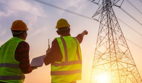 The above stock photo shows two workers inspecting the electricity high-voltage pole.