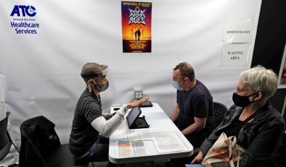 People are interviewed before receiving the Pfizer COVID-19 vaccine at the ATC Vaccination Services site in New York's Times Square on April 12.