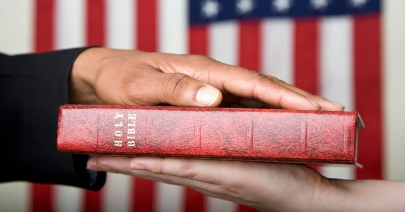 This stock image portrays a person swearing on the Bible in front of an American flag. HarperCollins Christian Publishing, Zondervan's parent company, retracted an agreement to print a "God Bless the USA" Bible edition.