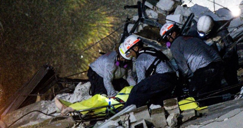 Emergency crews remove a covered stretcher bearing the body of a victim of Thursday morning's condominium collapse in Surfside, Florida.