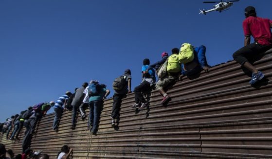 A group of Central American migrants -- mostly Hondurans -- climb a metal barrier on the Mexico-U.S. border near El Chaparral border crossing, in Tijuana, Baja California State, Mexico, on Nov. 25, 2018.