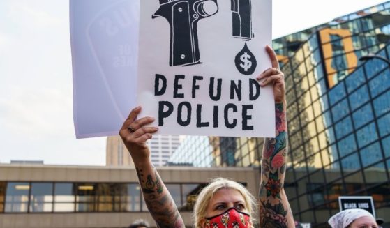 A protester holds a sign reading "Defund the Police" outside Hennepin County Government Plaza during a demonstration against police brutality and racism on Aug. 24, 2020, in Minneapolis, Minnesota.