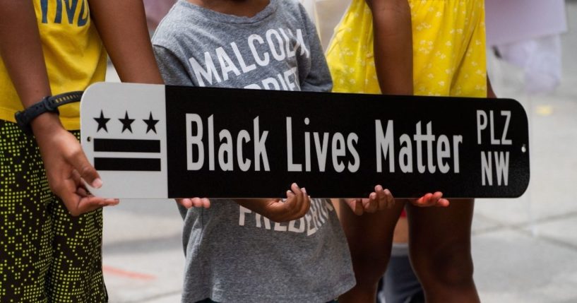 Children pose for a photograph with a Black Lives Matter Plaza street sign at Black Lives Matter Plaza in Washington, D.C., on June 19, 2021, during a Juneteenth celebration.