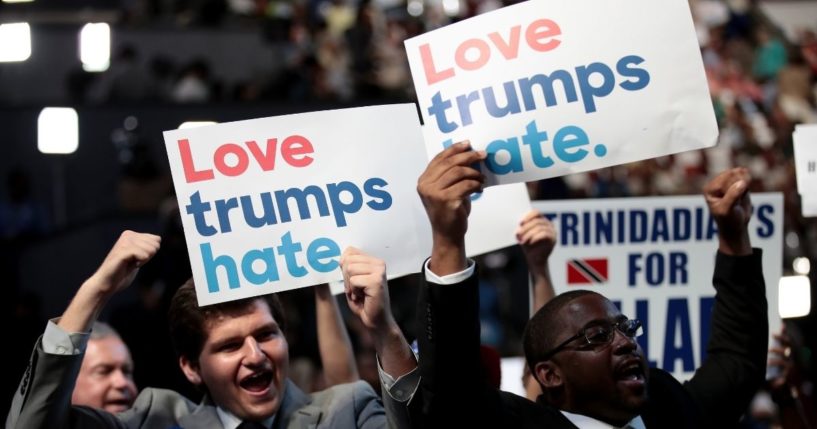 Delegates hold up signs that read "love trumps hate" during the opening of the first day of the Democratic National Convention at the Wells Fargo Center on July 25, 2016, in Philadelphia.