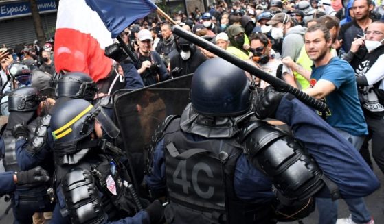 Protesters stand in front of riot police during a demonstration against French legislation making a COVID-19 health pass compulsory to visit a cafe, board a plane or travel on an inter-city train in Paris on Saturday.