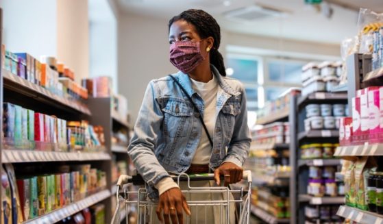 The above stock photo shows a customer at a grocery store with a face mask on.