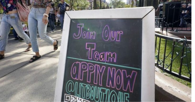 Pedestrians walk past a sign inviting people to apply for employment at a shop in Boston's fashionable Newbury Street neighborhood on Monday.