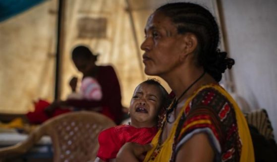 In this Tuesday, May 11, 2021 photo, Roman Kidanemariam, 35, holds her malnourished daughter, Merkab Ataklti, 22 months old, in the treatment tent of a medical clinic in the town of Abi Adi, in the Tigray region of northern Ethiopia.