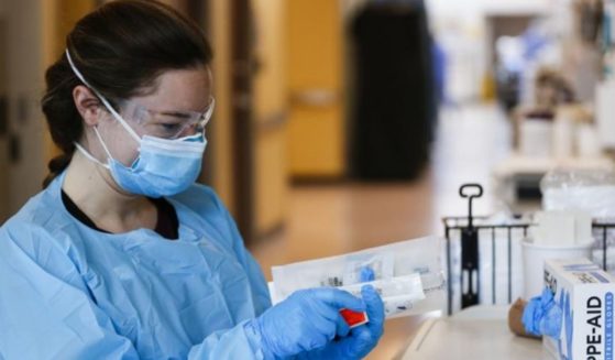 Nurses and doctors in the CoxHealth Emergency Department in Springfield, Missouri, don personal protective equipment to treat patients with COVID-19 on Friday.