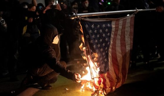 Black bloc protesters burn an American flag on Nov. 4, 2020, in Portland, Oregon.