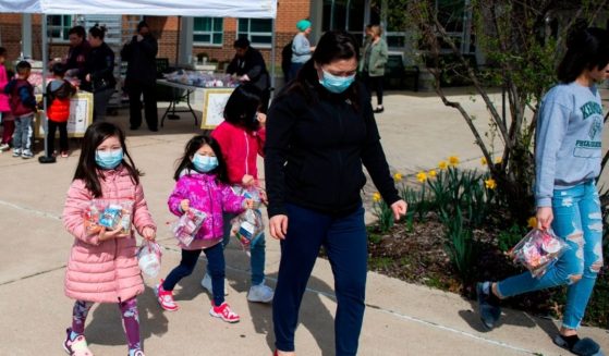 Children, some wearing face masks, pick up free lunch at Kenmore Middle School in Arlington, Virginia on March 16, 2020, after schools in the area closed due to the coronavirus outbreak.