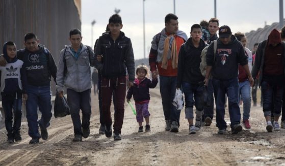 Central American immigrants walk between a newly built Bollard-style border fence, left, and the older "legacy" fence after crossing the Rio Grande from Mexico on Feb. 1, 2019, in El Paso, Texas.