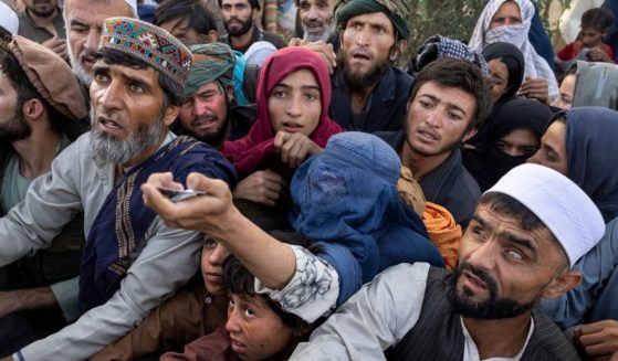 Displaced Afghans reach out for aid from a local Muslim organization at a makeshift IDP camp on Aug. 10, 2021, in Kabul, Afghanistan.