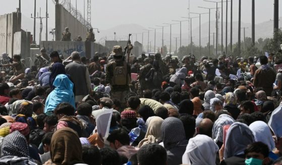 Afghans gather on a roadside near the military part of the airport in Kabul on Friday, hoping to flee from the country after the Taliban's military takeover.