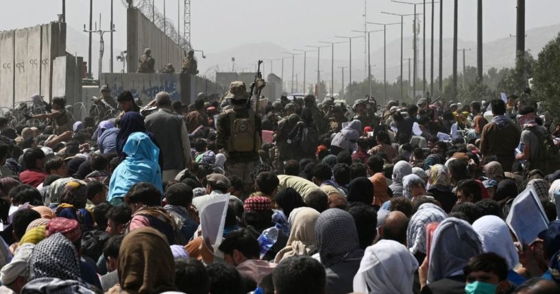 Afghans gather on a roadside near the military part of the airport in Kabul on Friday, hoping to flee from the country after the Taliban's military takeover.